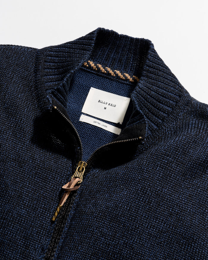 Close-up of a navy blue sweater with a brand label on a white background
