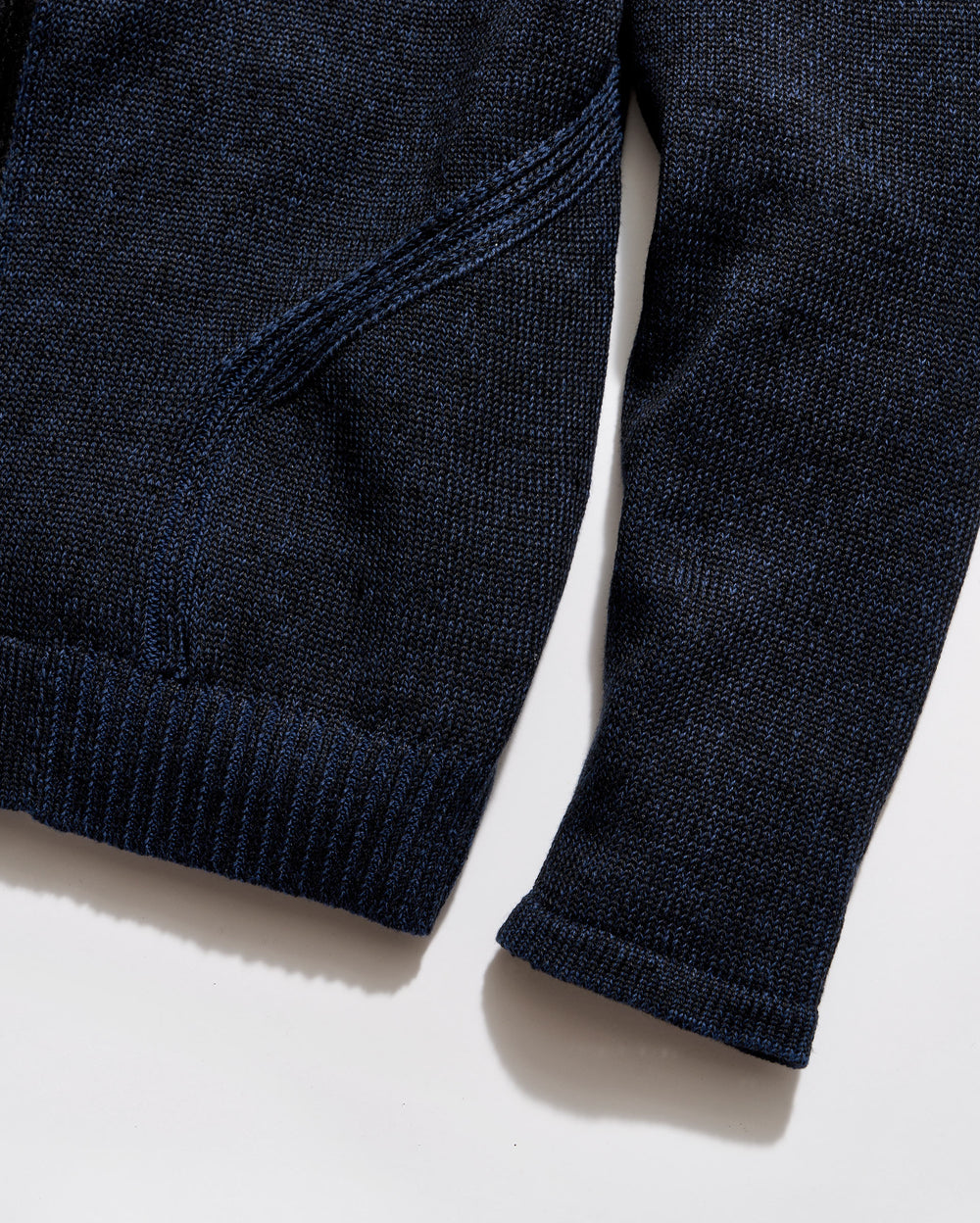 Close-up of a navy blue sweater on a light beige background