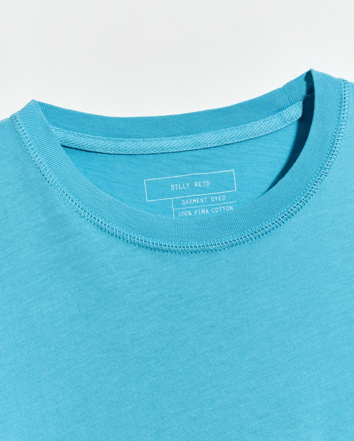 Close-up of a blue t-shirt with a brand label on the collar.