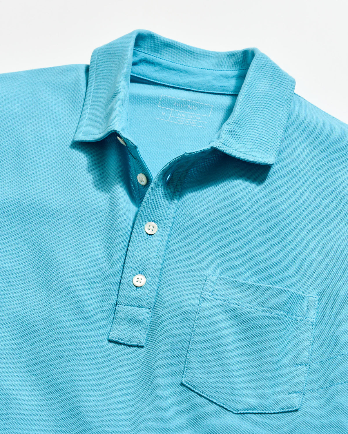 Close-up of a light blue polo shirt with buttons on a white background