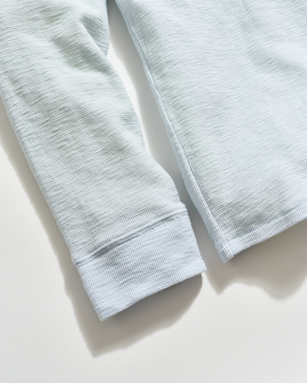 Close-up of light gray fabric with a textured pattern on a white background