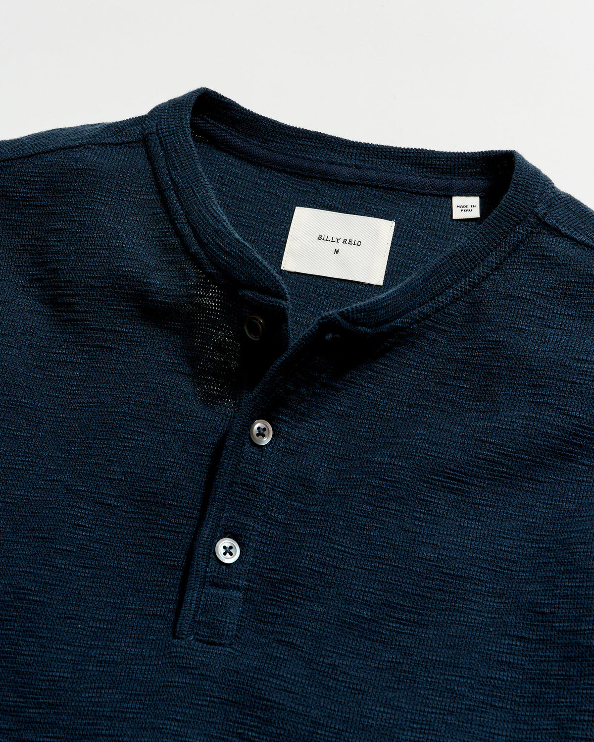 Navy blue polo shirt with brand label on a light gray background