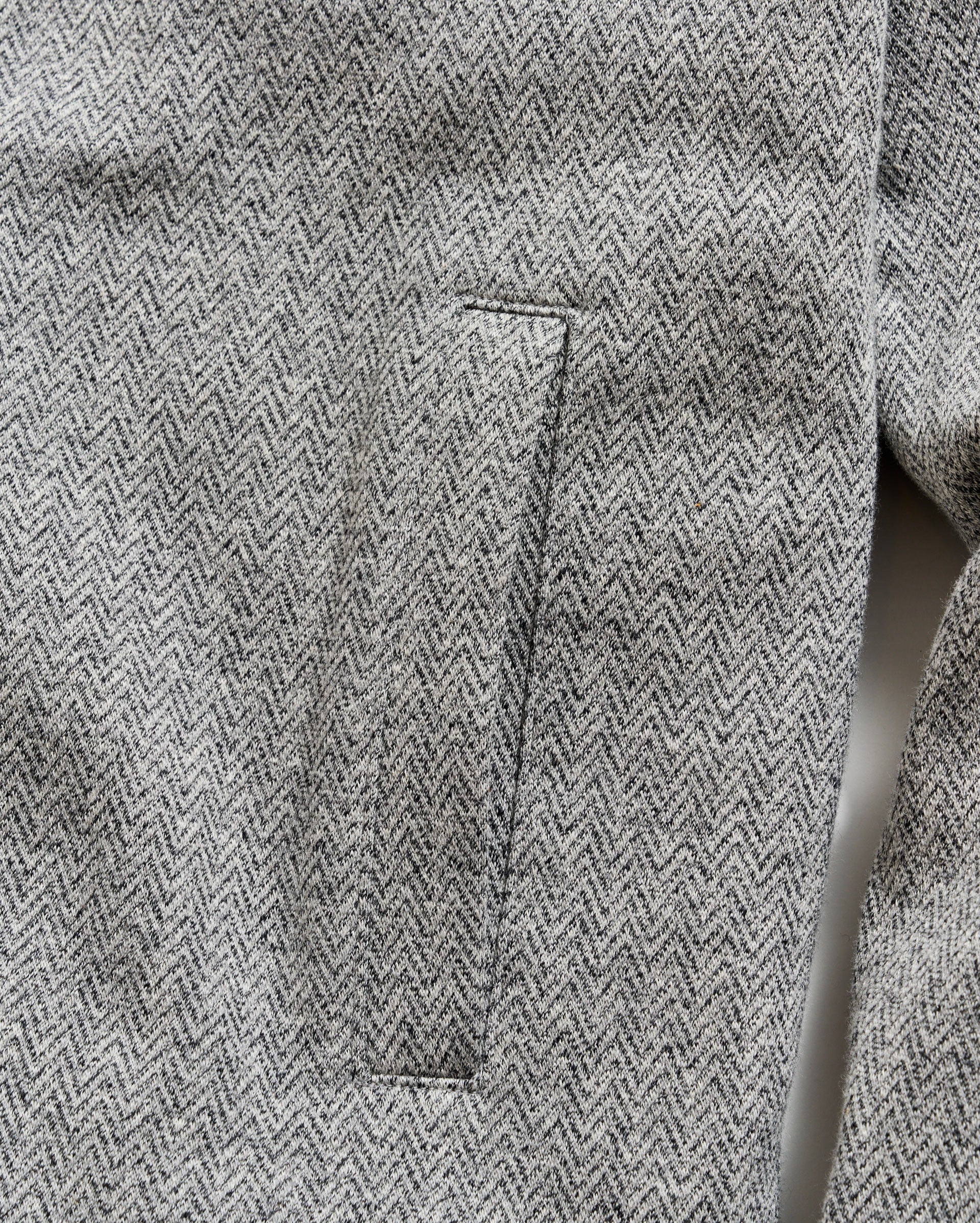 Close-up of a gray herringbone patterned fabric with a pocket detail.