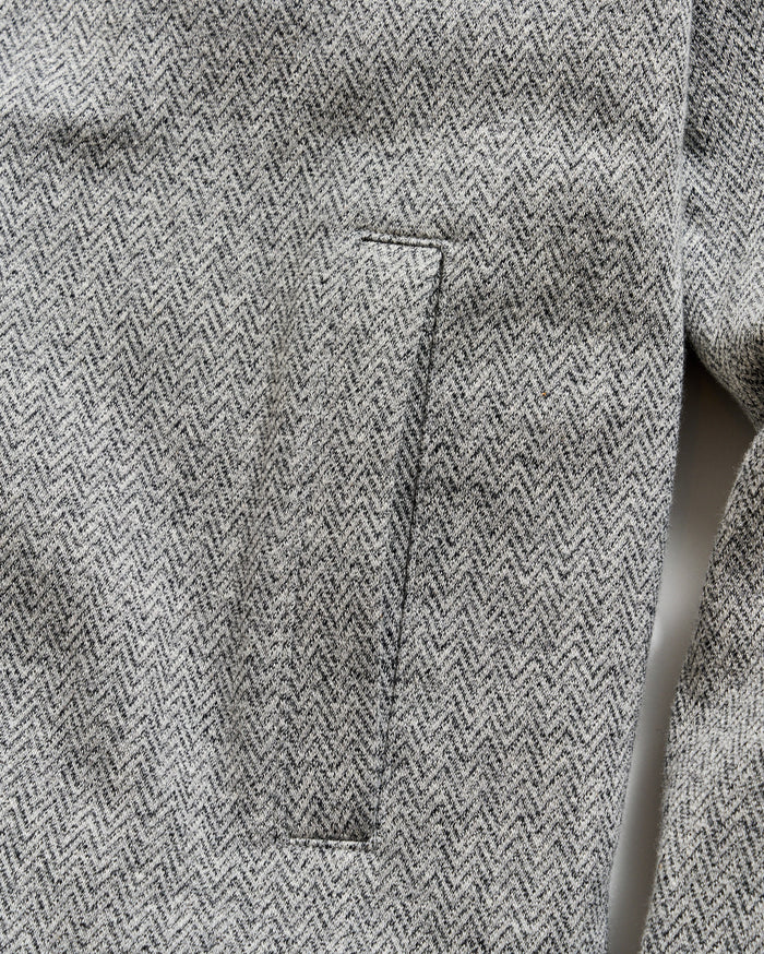 Close-up of a gray herringbone patterned fabric with a pocket detail.