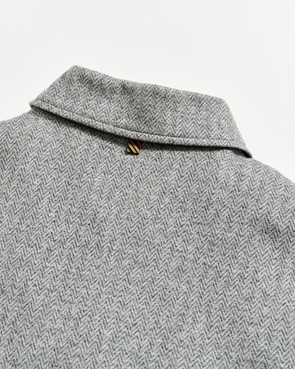 Close-up of a gray herringbone patterned fabric with a collar.