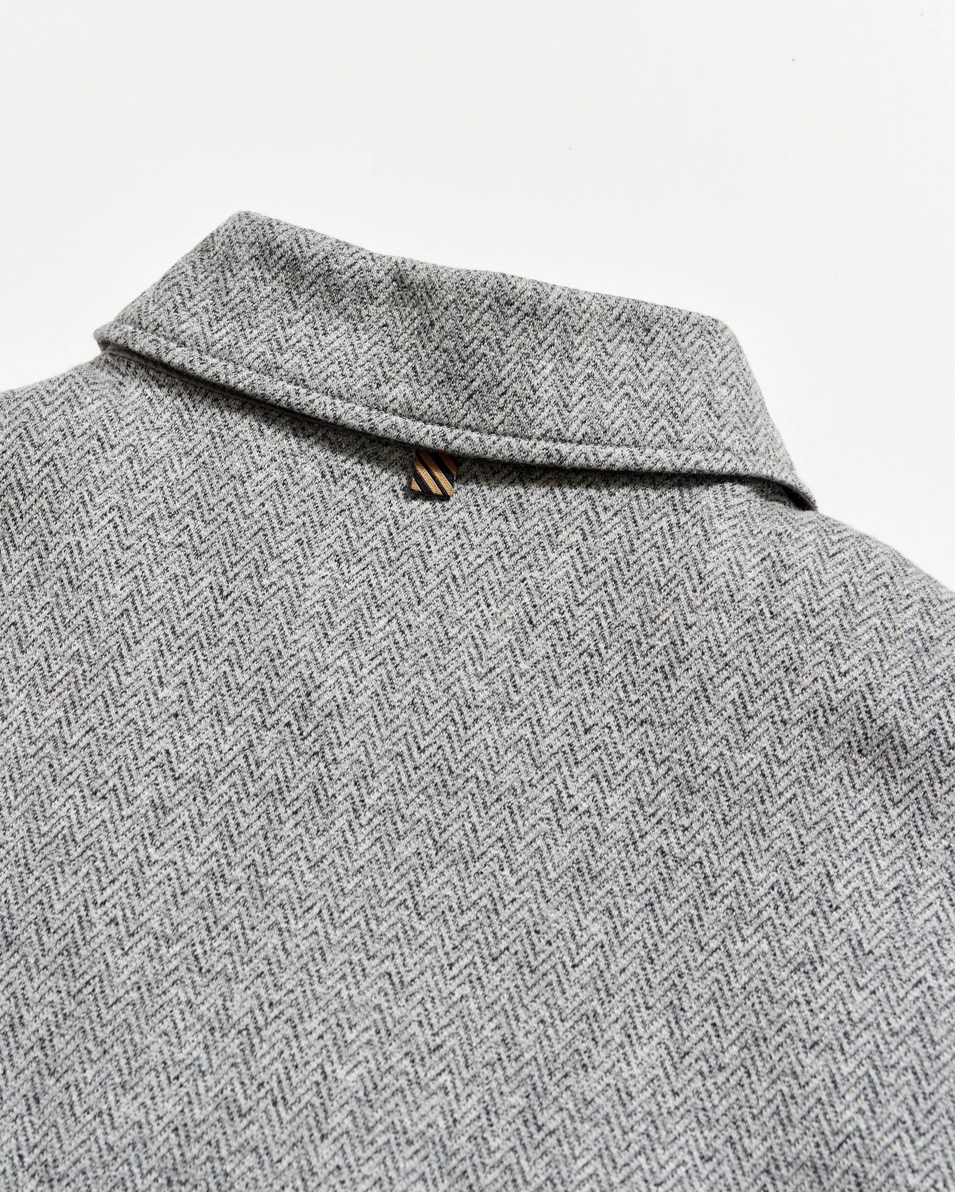 Close-up of a gray herringbone patterned fabric with a collar.