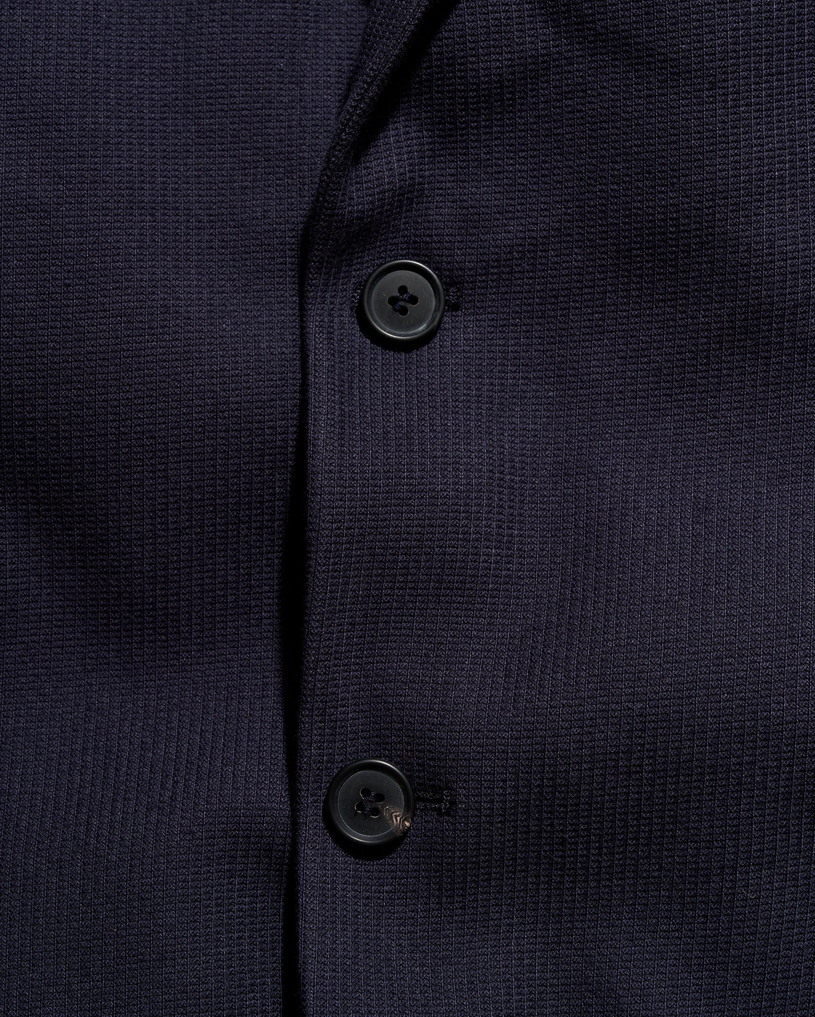 Close-up of a navy blue textured shirt with buttons.