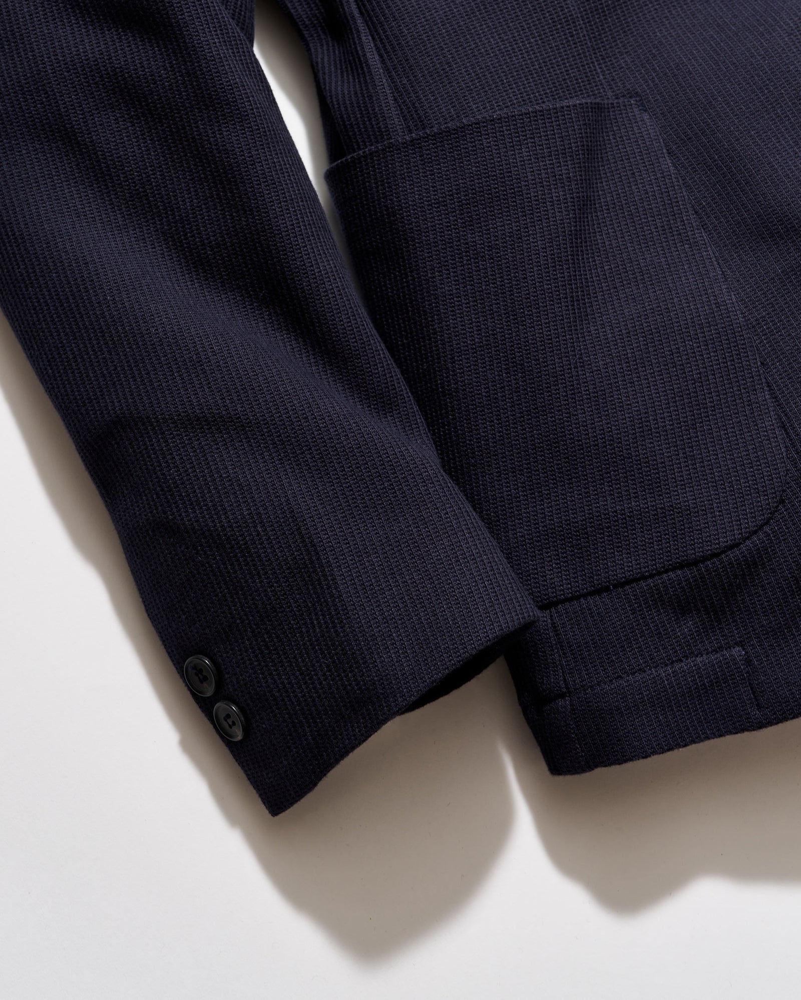 Navy blue textured jacket on a light beige background