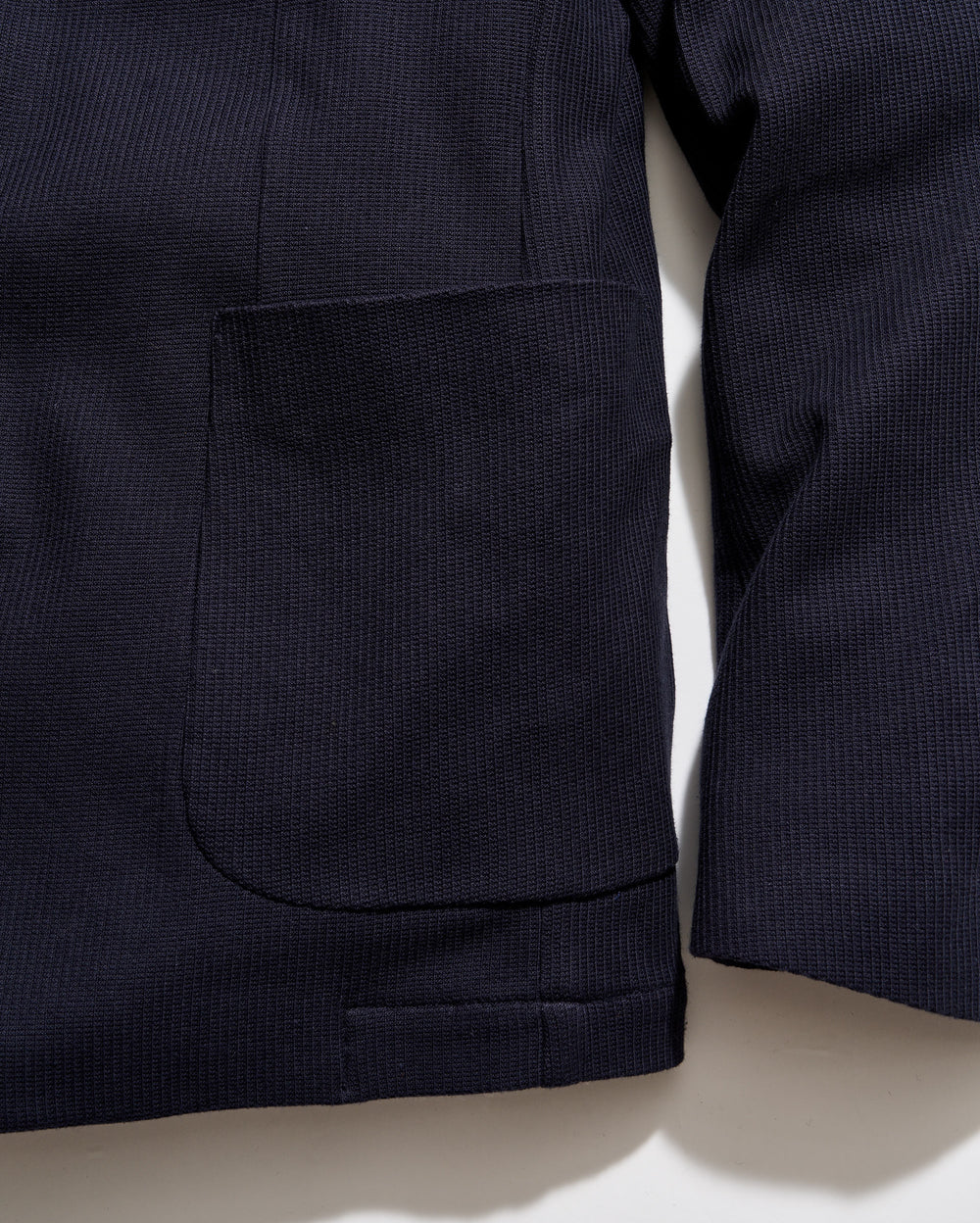 Close-up of a dark blue jacket with a pocket on a light beige background