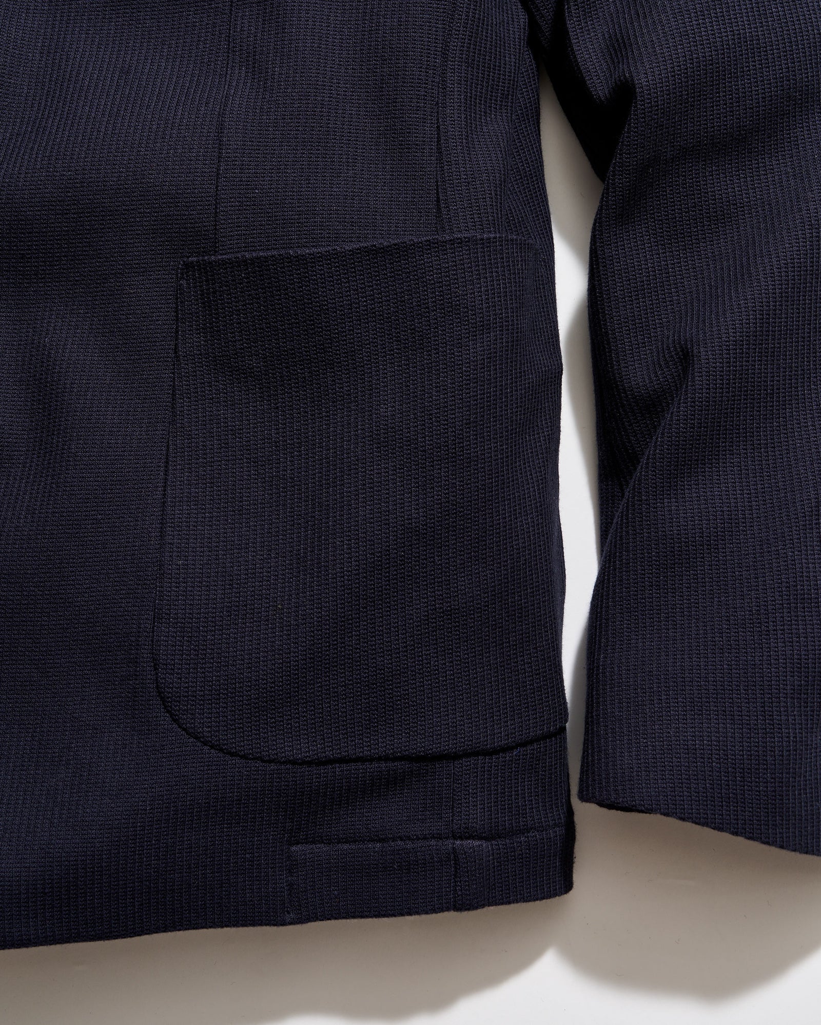 Close-up of a dark blue jacket with a pocket on a light beige background