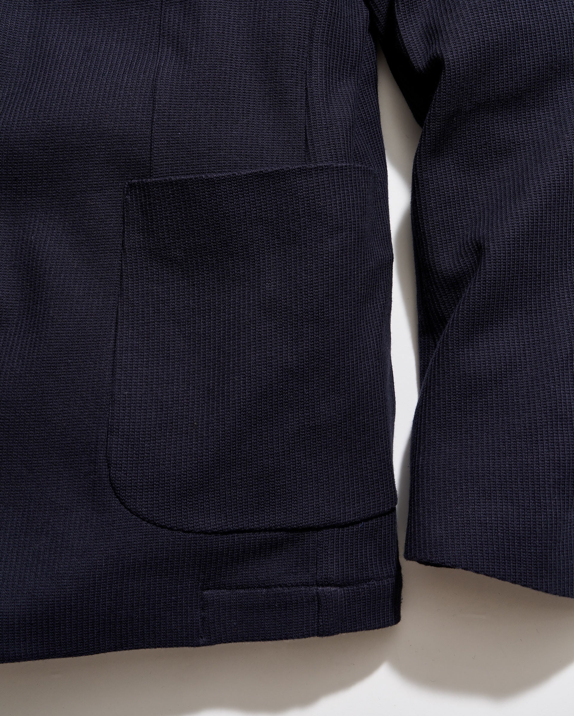 Close-up of a dark blue jacket with a pocket on a light beige background