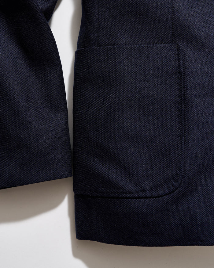 Close-up of a navy blue jacket with a pocket on a light beige background