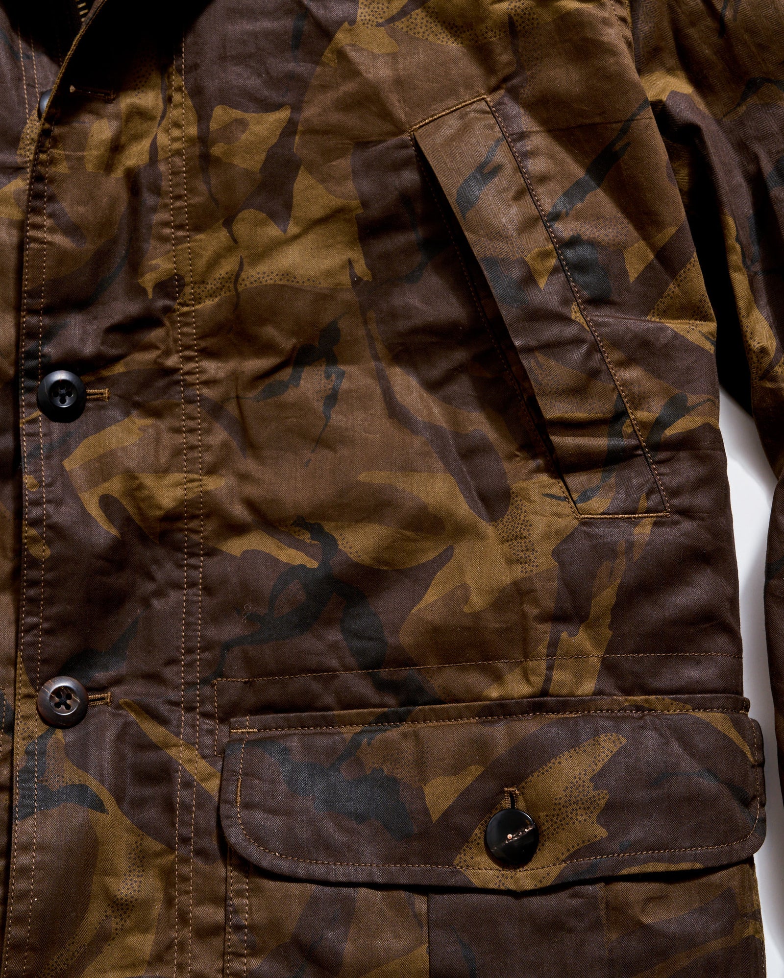 Close-up of a camouflage-patterned jacket with buttons on a white background