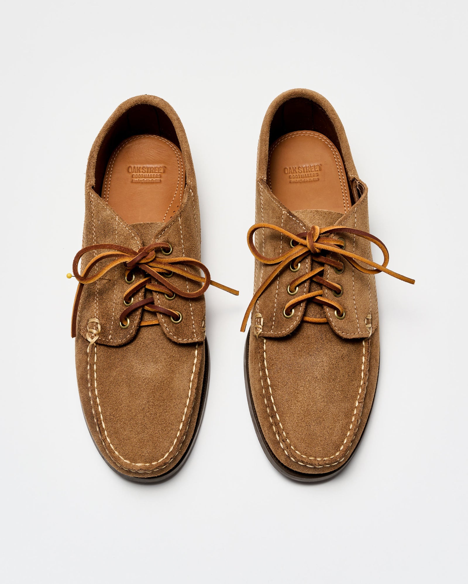 Pair of brown suede shoes with leather laces on a white background