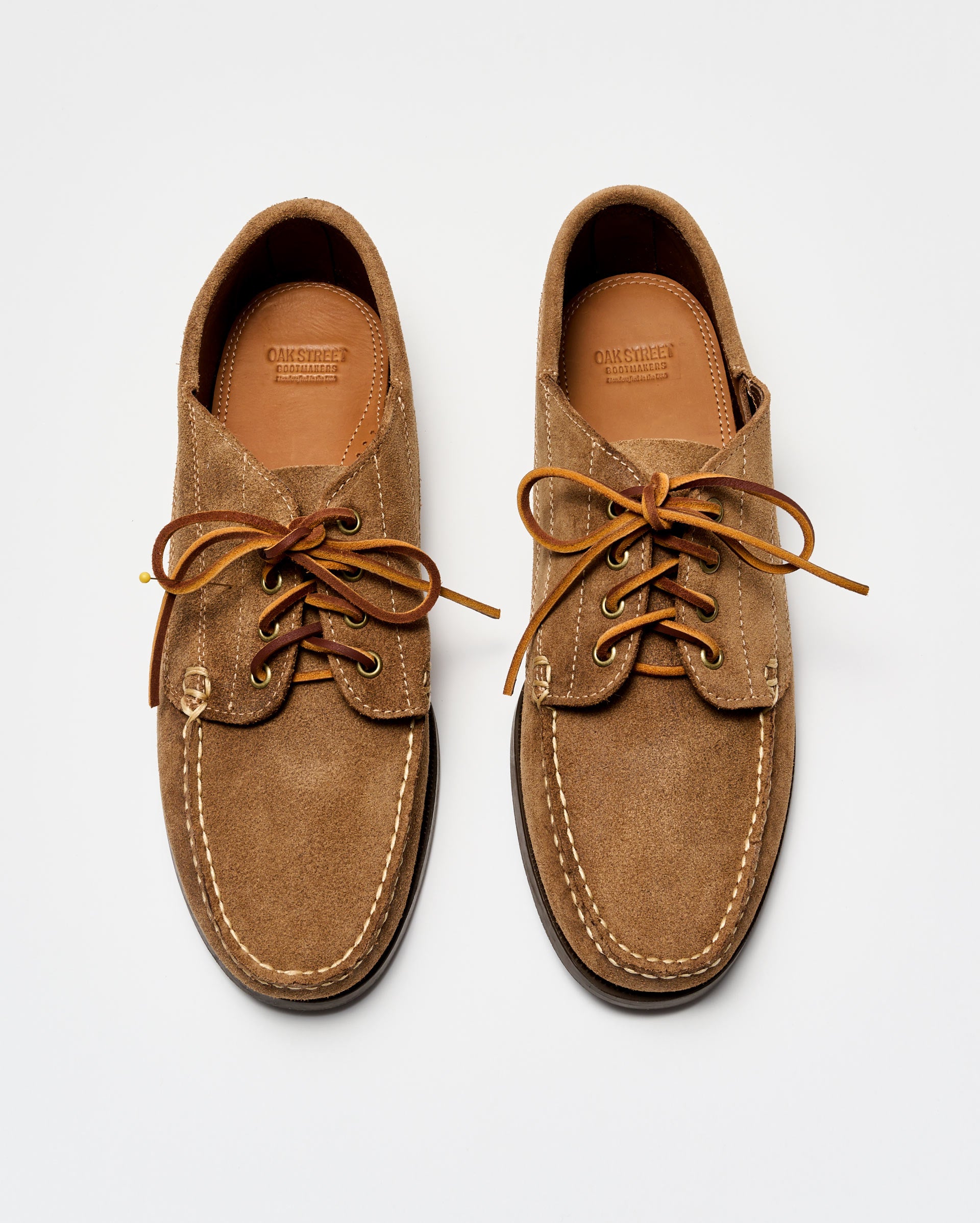 Pair of brown suede shoes with leather laces on a white background