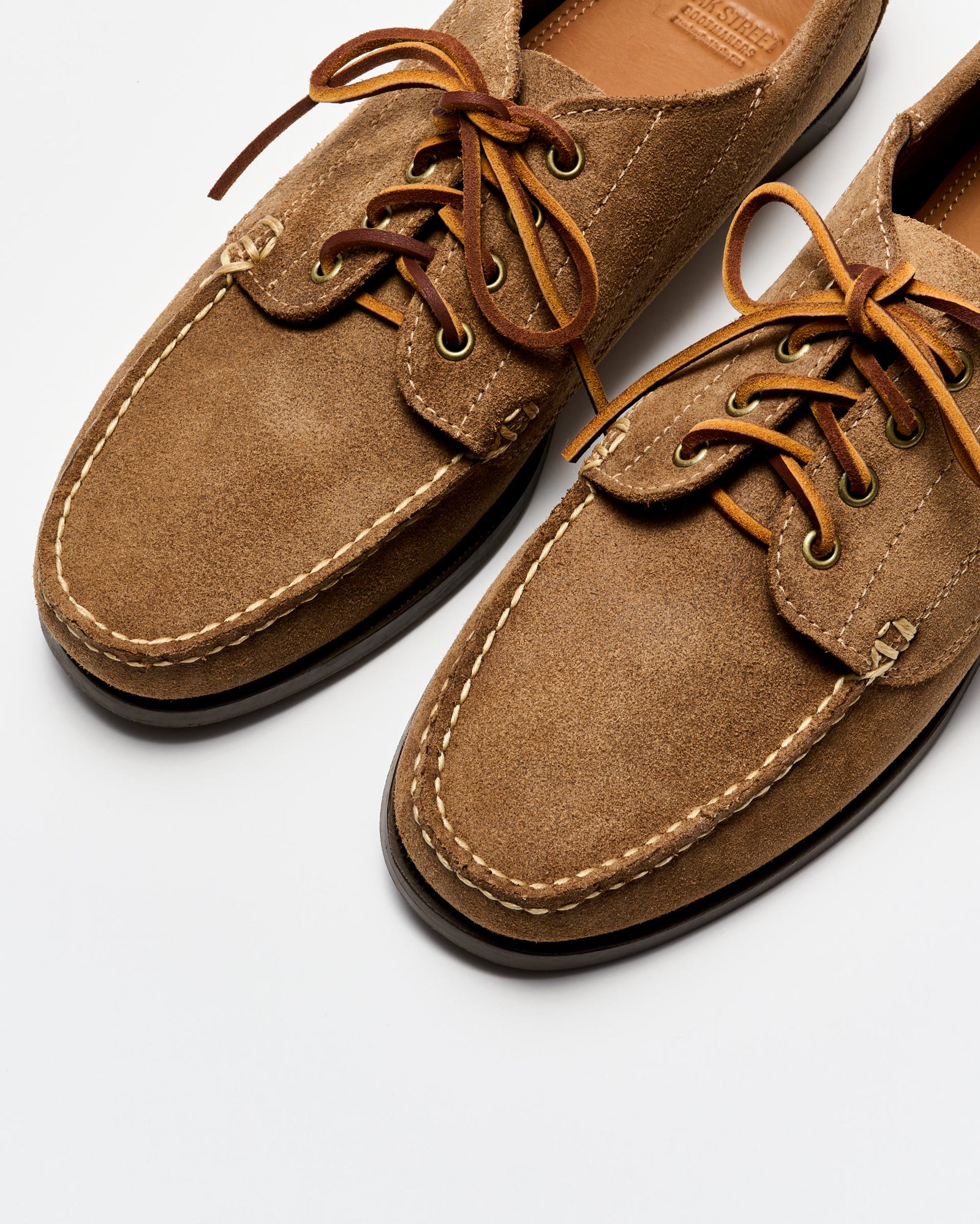 Pair of brown suede shoes with laces on a white background