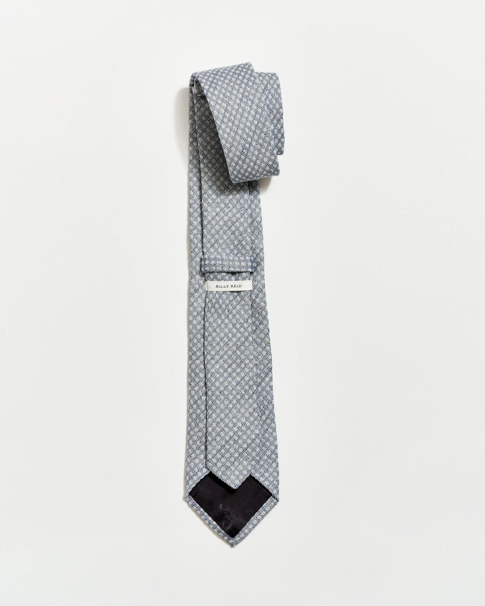 Patterned tie with a brand label on a light gray background