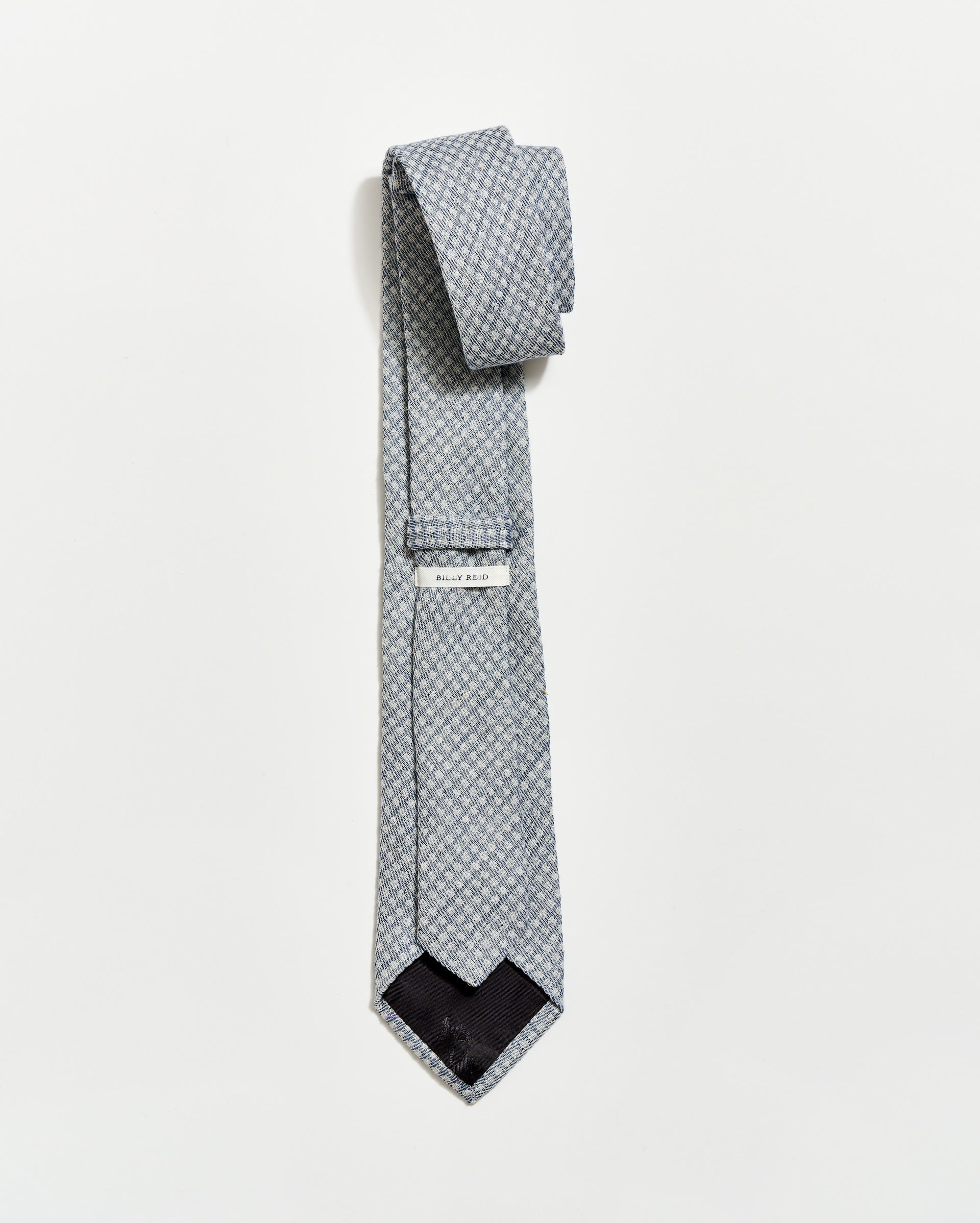 Patterned tie with a brand label on a light gray background
