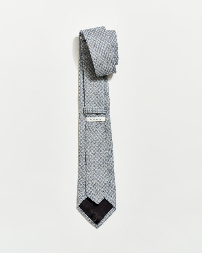 Patterned tie with a brand label on a light gray background