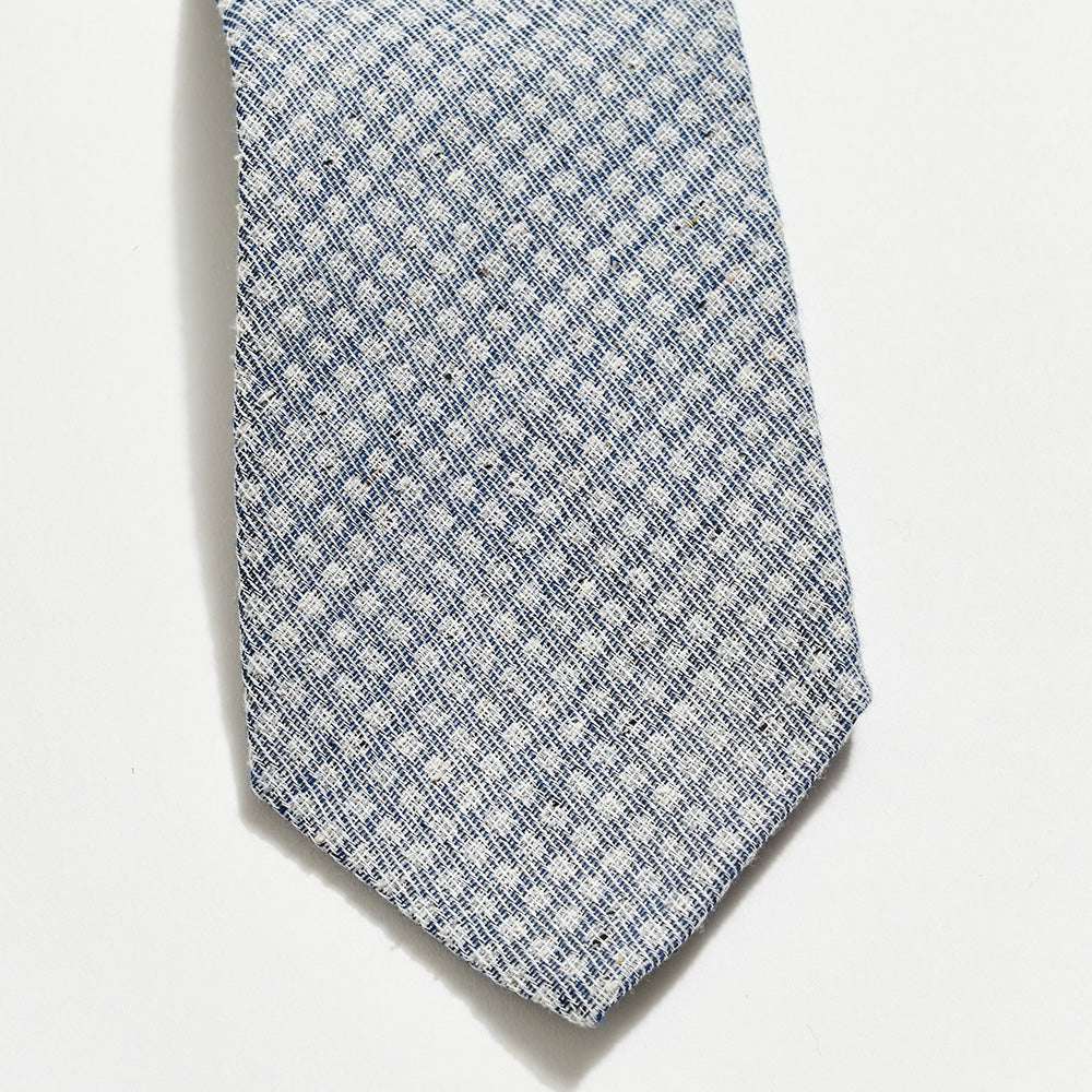 Blue patterned tie on a light gray background