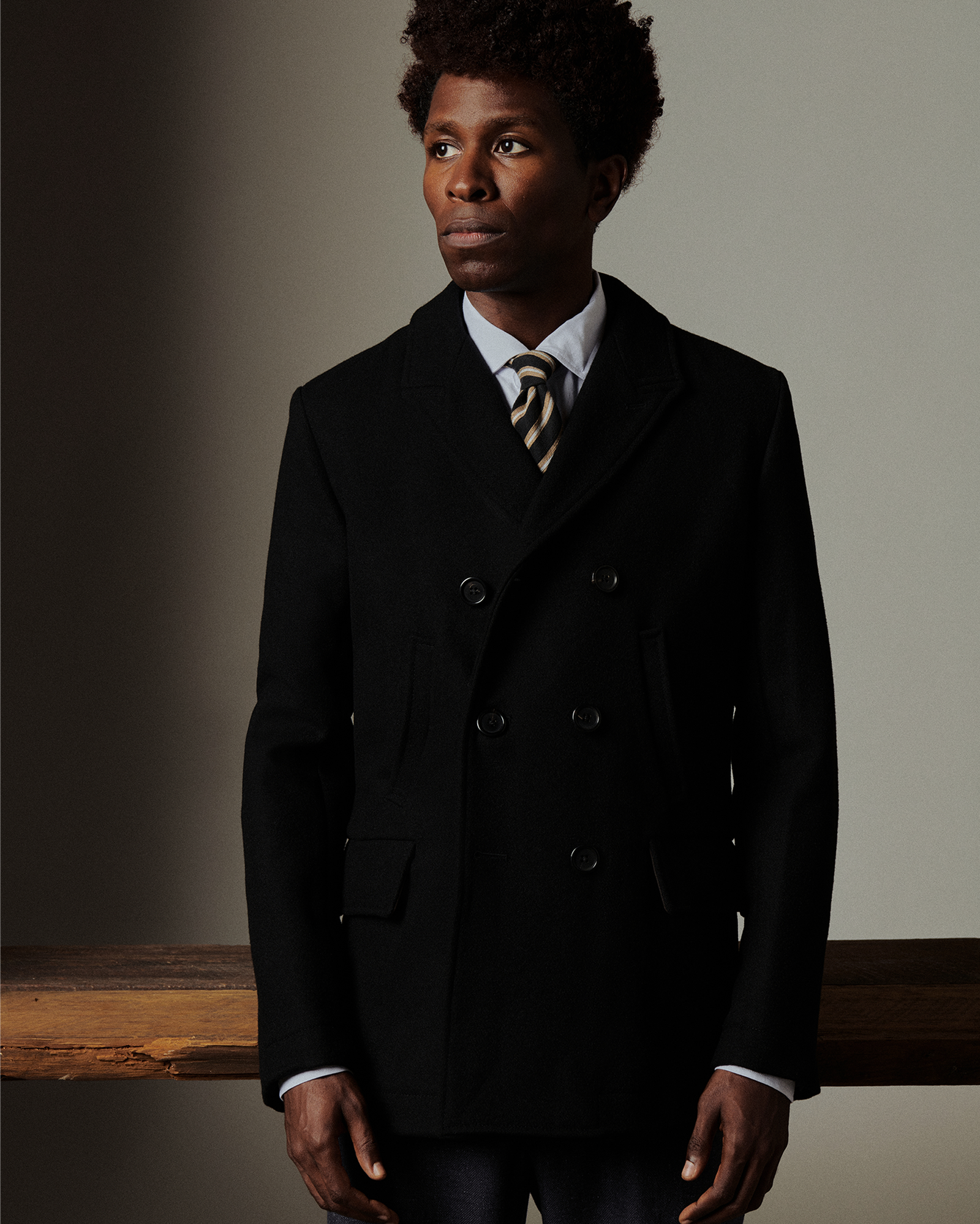 Man wearing a dark coat and tie against a plain background