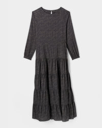 A long-sleeve, dark gray tiered midi dress with a subtle floral print and a round neckline, displayed on a plain white background.