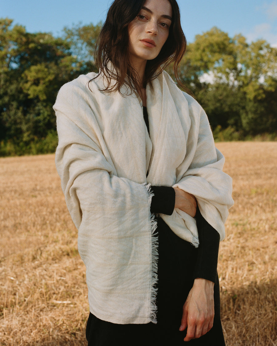 Female model wearing the Herringbone Ribbon Blanket in Grey and Natural
