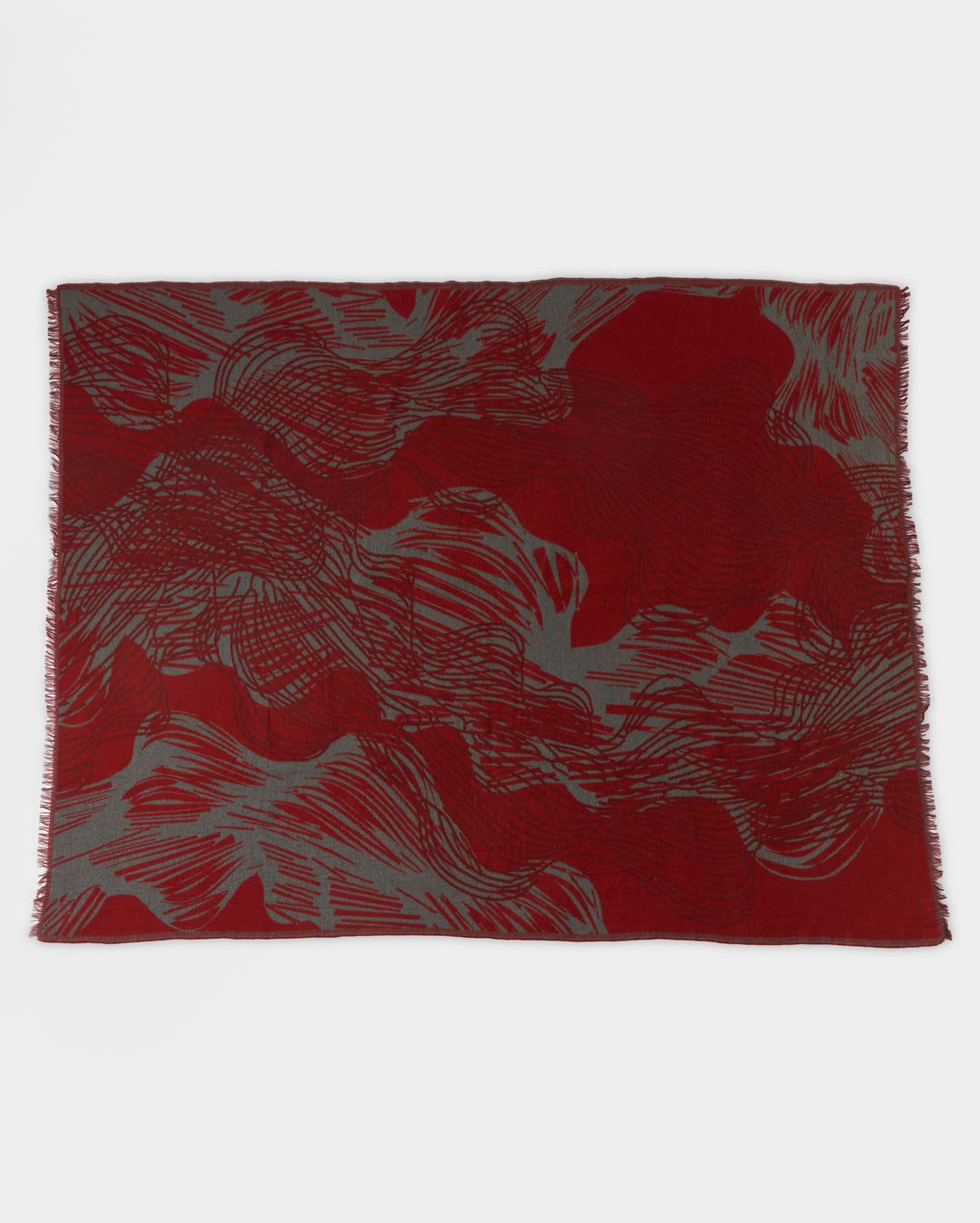 A rectangular textile with an abstract pattern in deep red and gray tones, featuring wavy, swirling lines across the surface and lightly fringed edges.