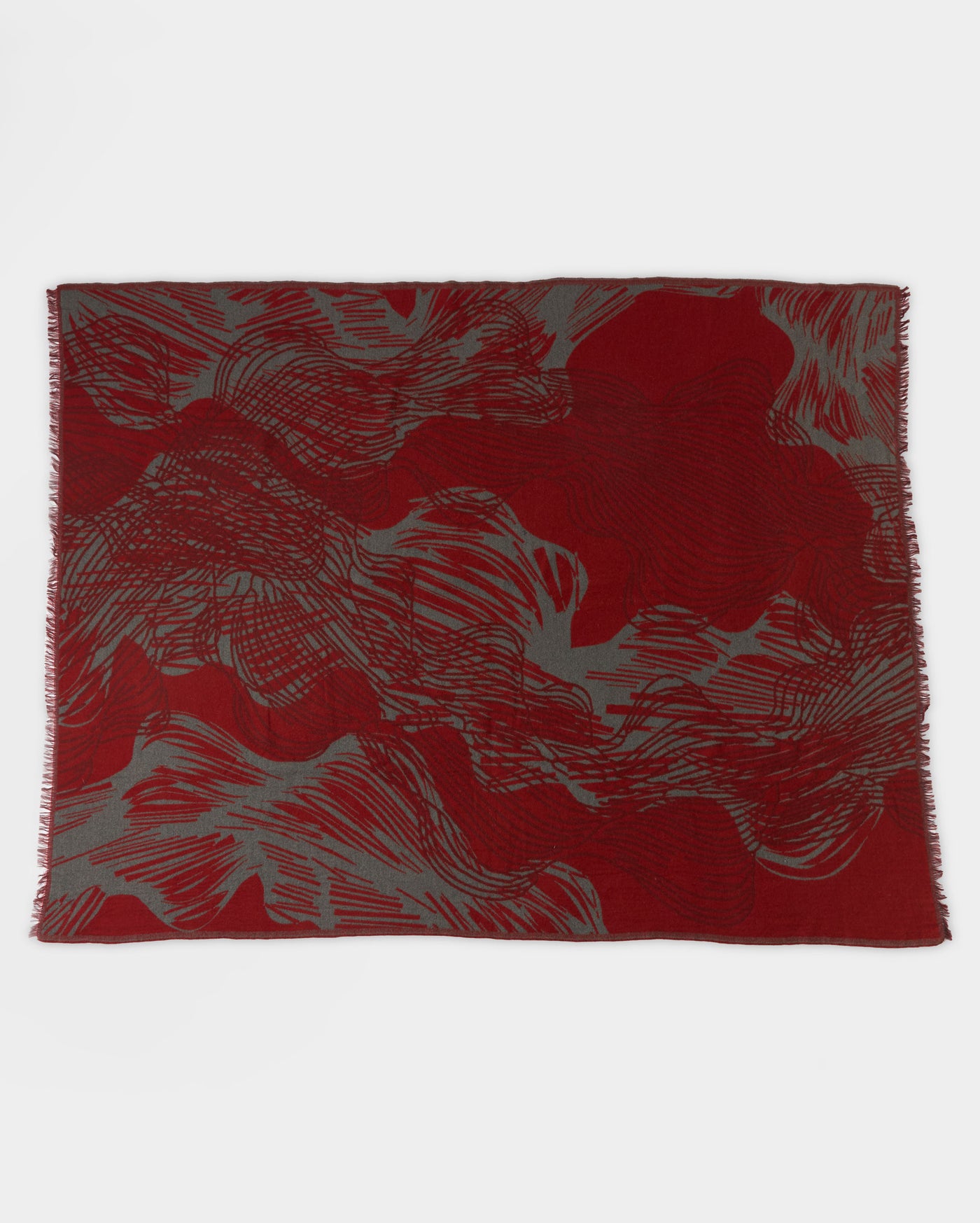 A rectangular textile with an abstract pattern in deep red and gray tones, featuring wavy, swirling lines across the surface and lightly fringed edges.