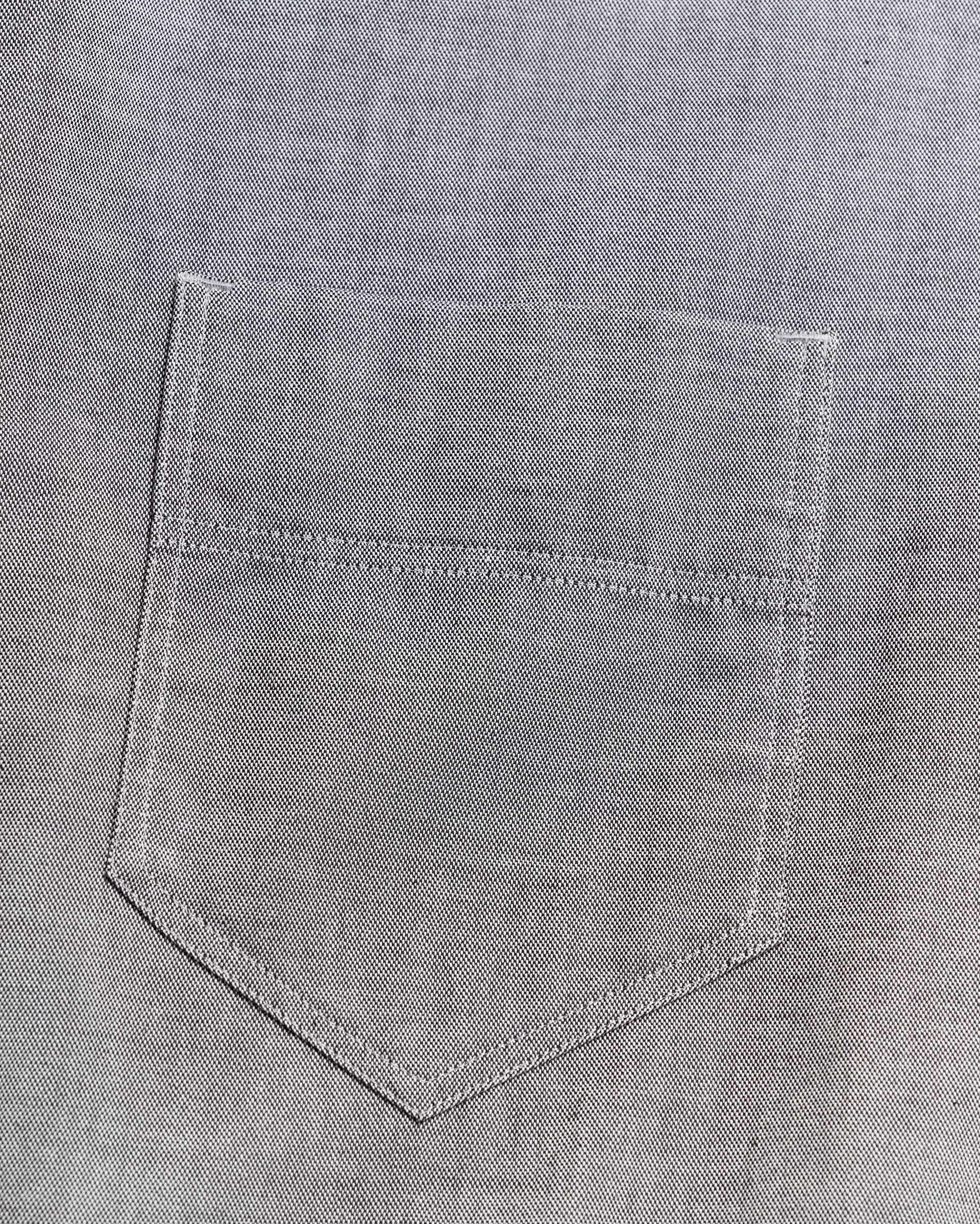 Close-up of a gray denim fabric with a stitched pocket, showing detailed texture and visible seam lines.