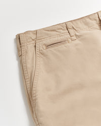 Close-up of the upper section of beige khaki pants, showing a single back pocket with a buttonhole detail, belt loops, and visible stitching on light background.